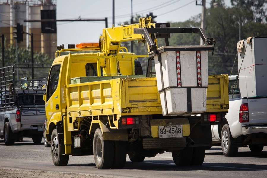 A yellow utility bucket truck driving on a road among traffic.